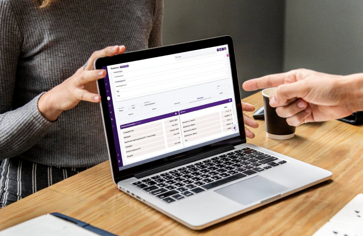 Zwei Personen besprechen Produktentwicklungsdaten in der geöffneten UMYNO Software-Plattform auf einem Laptop.